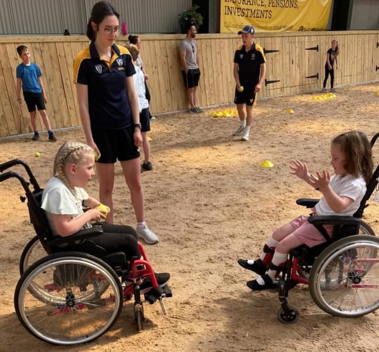 Two girls in wheelchairs playing catch
